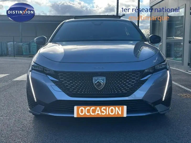 Peugeot 308 gris Artense vue de face, avec calandre noire et feux LED verticaux allumés.