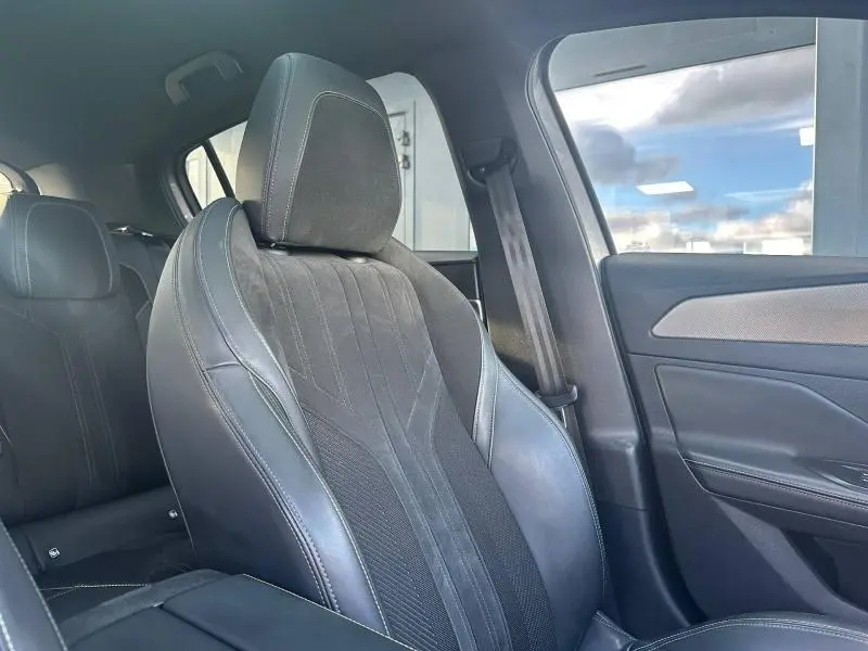 Vue intérieure côté droit sur le siège avant en cuir et tissu noir de la Peugeot 308 GT 2022, avec porte et ceinture visibles.