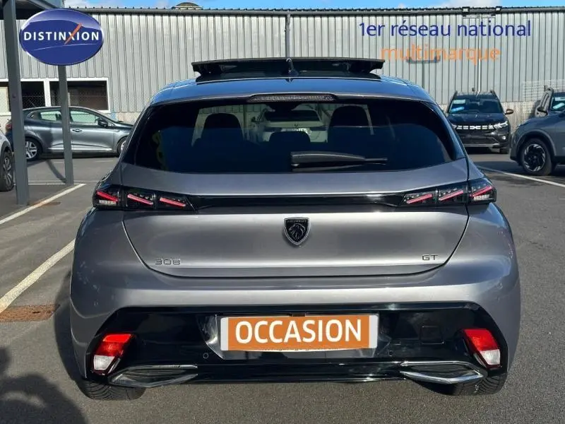 Vue arrière d'une Peugeot 308 GT gris Artense avec feux LED distinctifs et logo noir, stationnée en extérieur.