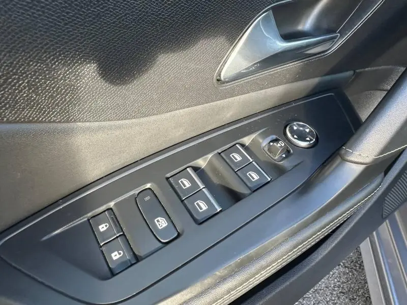 Gros plan sur la commande des vitres et rétroviseurs côté conducteur de la Peugeot 308 gris Artense, intérieur noir.