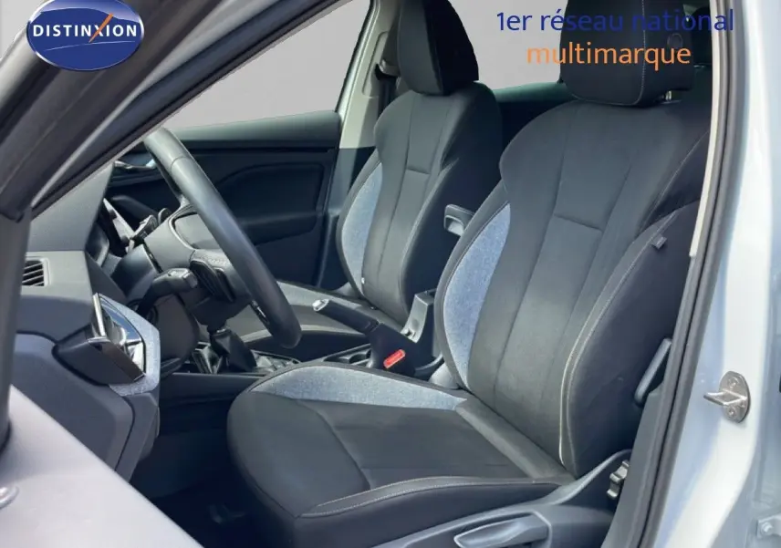 Vue intérieure côté conducteur de la Skoda Scala blanc glacier, sièges tissu gris et noir avec volant cuir multifonction.