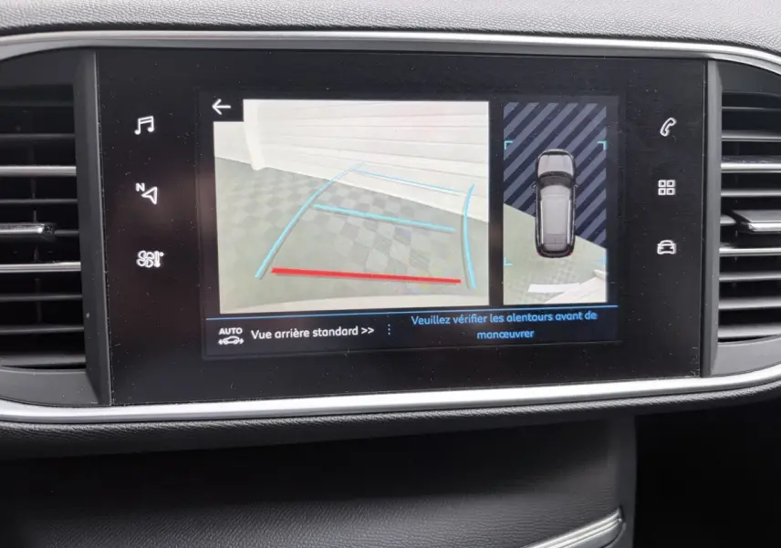 Écran tactile central affichant la caméra de recul et l’aide au stationnement du Peugeot 308 gris foncé, vue intérieure.