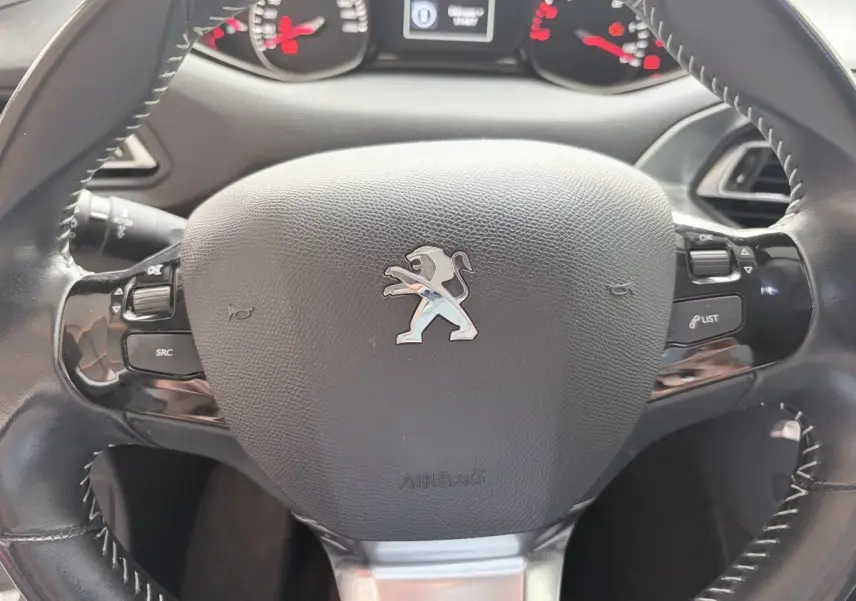 Volant cuir noir multi-fonctions Peugeot 308 BlueHDi 130 S&S Allure, avec logo lion et commandes intégrées.