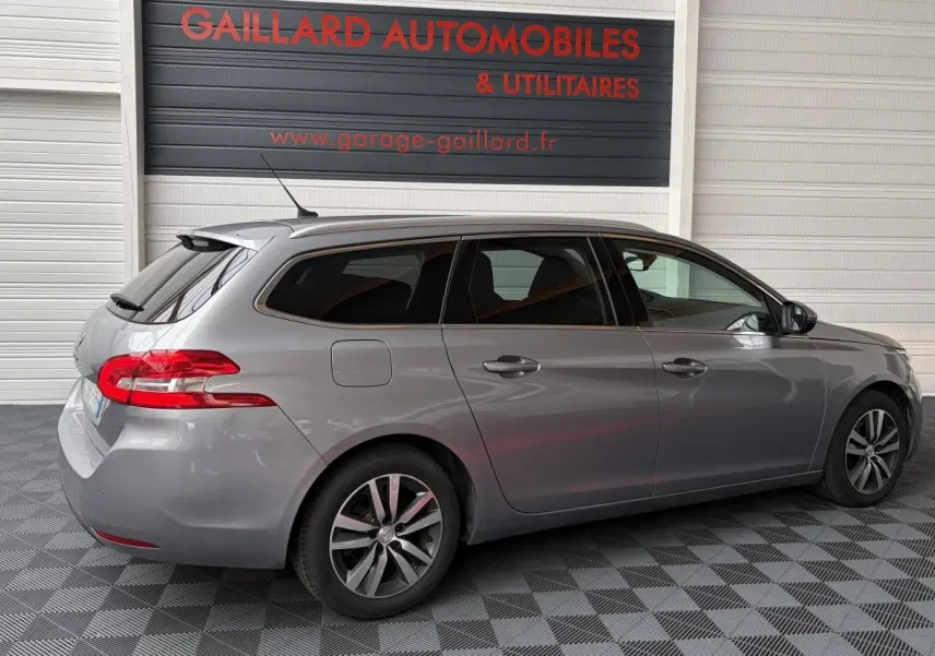 Peugeot 308 gris foncé vue de profil côté droit, break avec feux arrière rouges et jantes alliage.