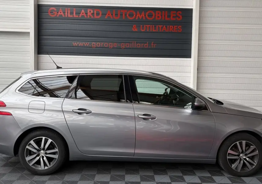 Peugeot 308 BlueHDi 130 gris foncé vue de profil côté gauche, avec jantes alliage et vitres teintées.