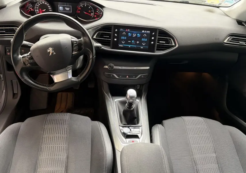 Vue intérieure avant de la Peugeot 308 gris foncé, volant cuir multifonctions et écran tactile central visible.