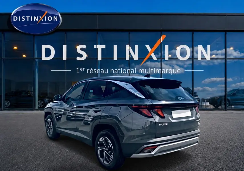 Vue 3/4 arrière droite du Hyundai Tucson gris ecotronique avec jantes alliage et feux arrière LED, devant une vitrine Distinxion.