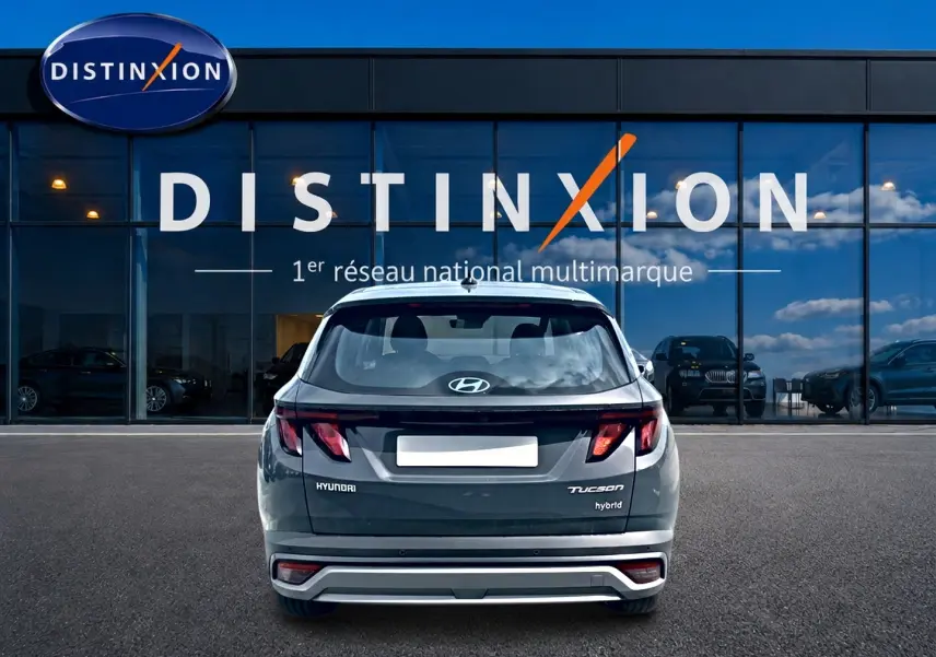 Vue arrière d'un Hyundai Tucson gris ecotronique hybride stationné devant une vitrine Distinxion.