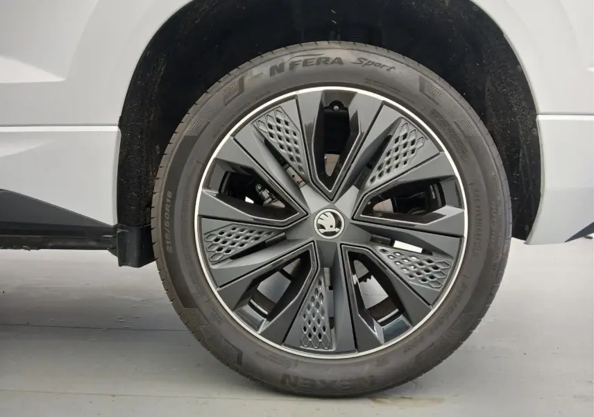 Gros plan sur la roue avant droite du Skoda Karoq blanc lune, mettant en valeur la jante design Sportline.