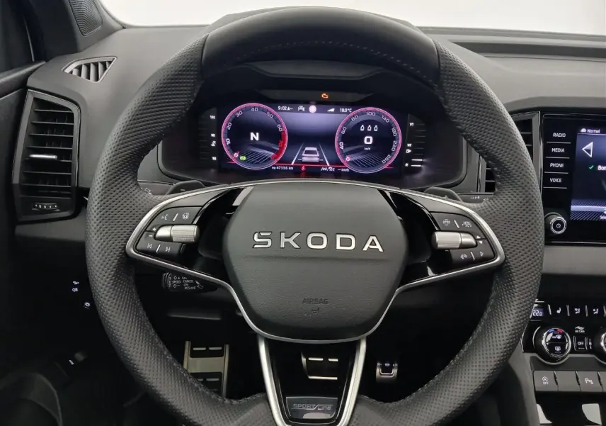 Vue rapprochée du volant SKODA KAROQ 1.5 TSI 150 DSG7 Sportline avec tableau de bord numérique et commandes intégrées.