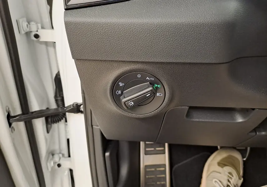 Gros plan sur le bouton de commande des phares à gauche du volant dans un Skoda Karoq blanc lune 2025.