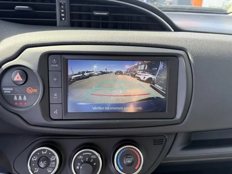 Vue intérieure du tableau de bord de la Toyota Yaris 2020, écran de caméra de recul et commandes de climatisation visibles.