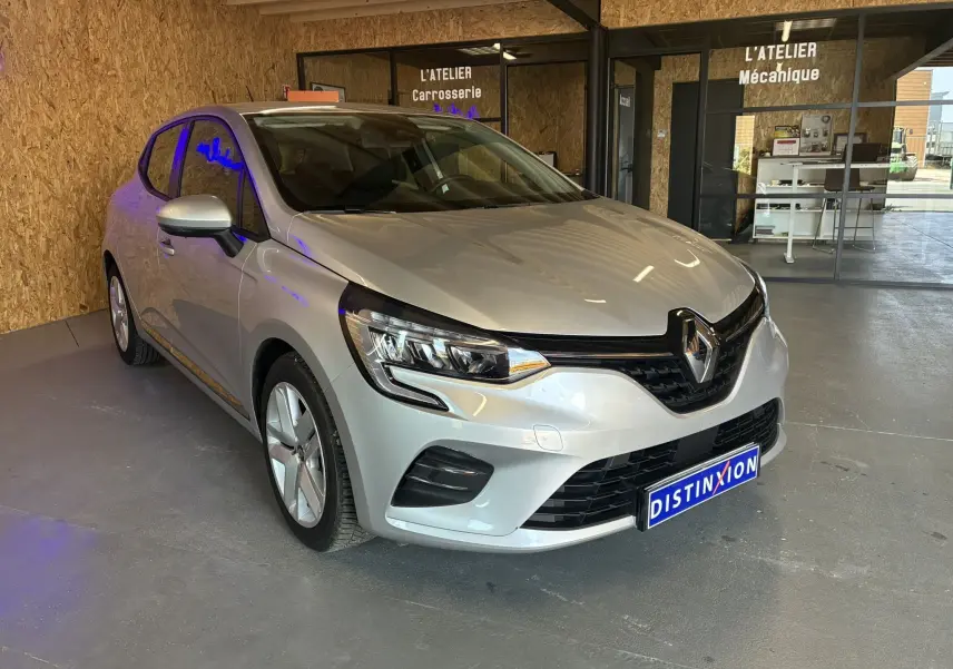 Renault Clio 1.5 Blue dCi Business gris vue 3/4 avant droit dans un atelier avec plaque Distinxion.