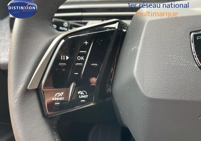Gros plan sur les commandes au volant noir brillant du Peugeot 3008 Hybrid 2025, finition Allure, intérieur gris.