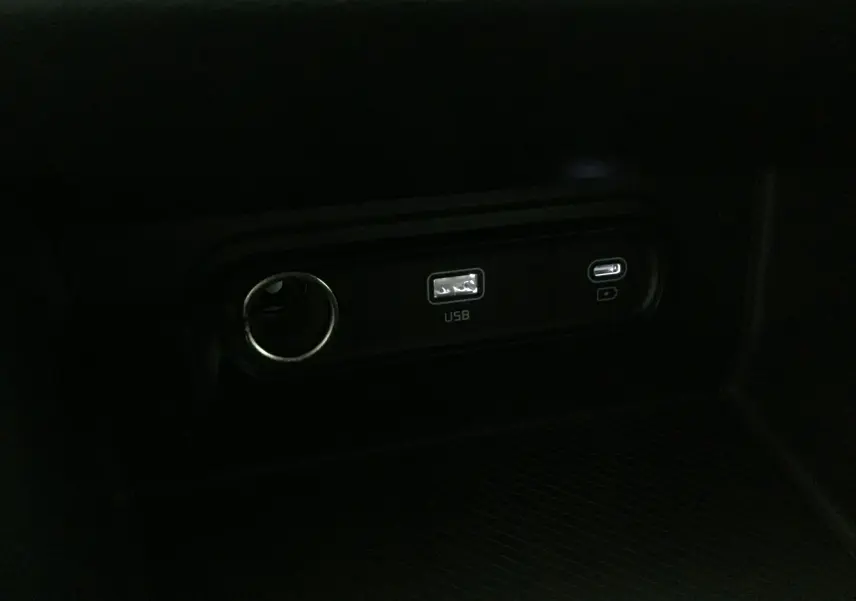 Prise USB et port 12V en gros plan dans l'habitacle sombre du Kia Sportage blanc 2025 DCT7 1.6 CRDI MHEV Style.