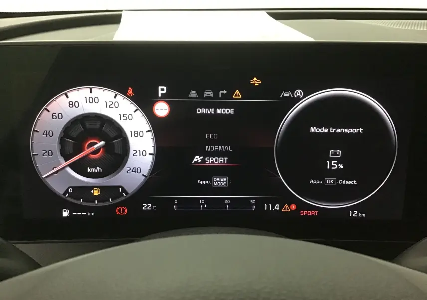 Tableau de bord digital 12,3'' du Kia Sportage blanc 2025 affichant mode sport et batterie à 15%
