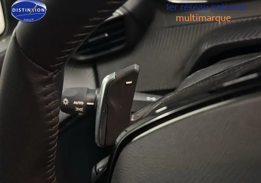 Gros plan sur la palette de changement de vitesse au volant d'une Peugeot 208 gris Artense, intérieur noir.