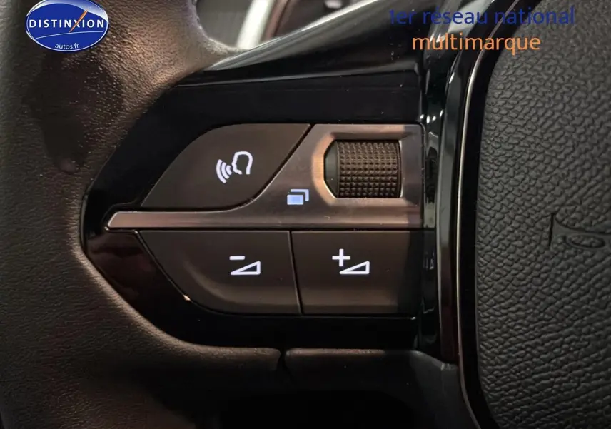 Gros plan sur les commandes audio au volant de la Peugeot 208 gris artense, version 2025 hybride.