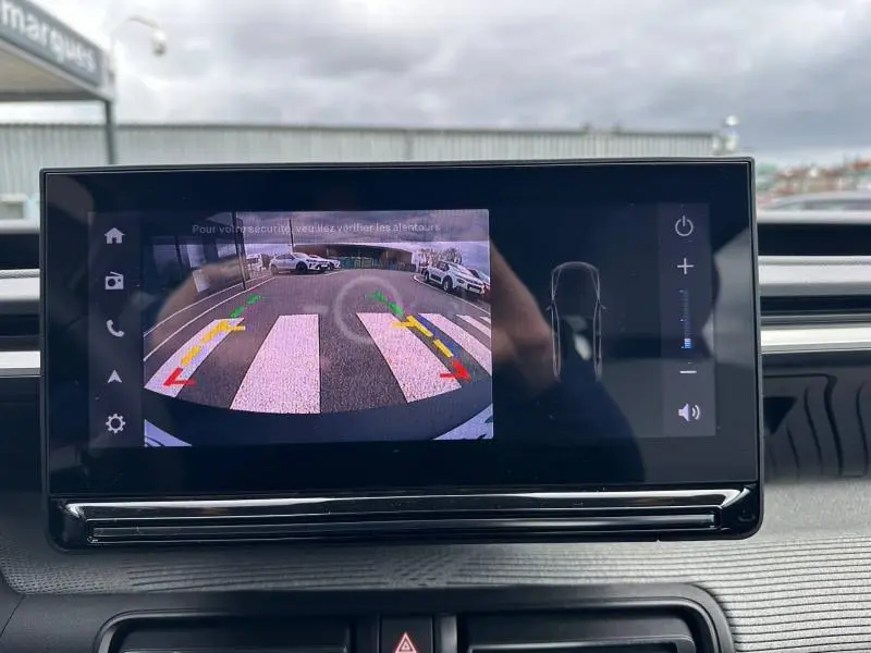 Écran central de la Citroën C3 2025 montrant la caméra de recul avec guidage dynamique sur un parking extérieur.