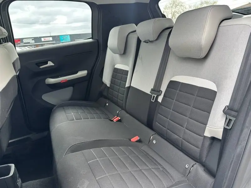 Vue intérieure arrière droite des sièges arrière gris clair et noir du Citroën C3 2025, avec appuie-têtes et ceintures visibles.