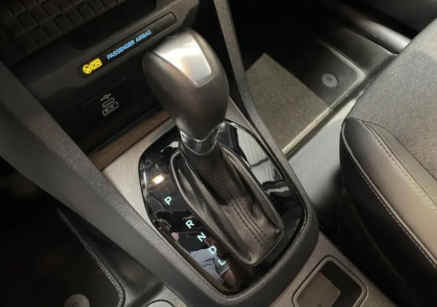 Le levier de vitesses automatique noir du Ford Tourneo Courier 2024, avec port USB-C et siège tissu gris visible.