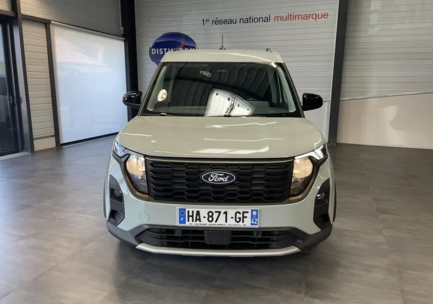 Vue avant du Ford Tourneo Courier gris clair avec calandre nid d'abeille noire et plaques d'immatriculation françaises.