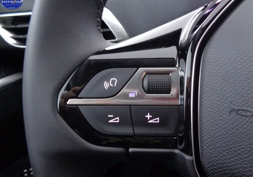Gros plan sur les commandes de volume et de reconnaissance vocale sur le volant noir du Peugeot 3008 2023.
