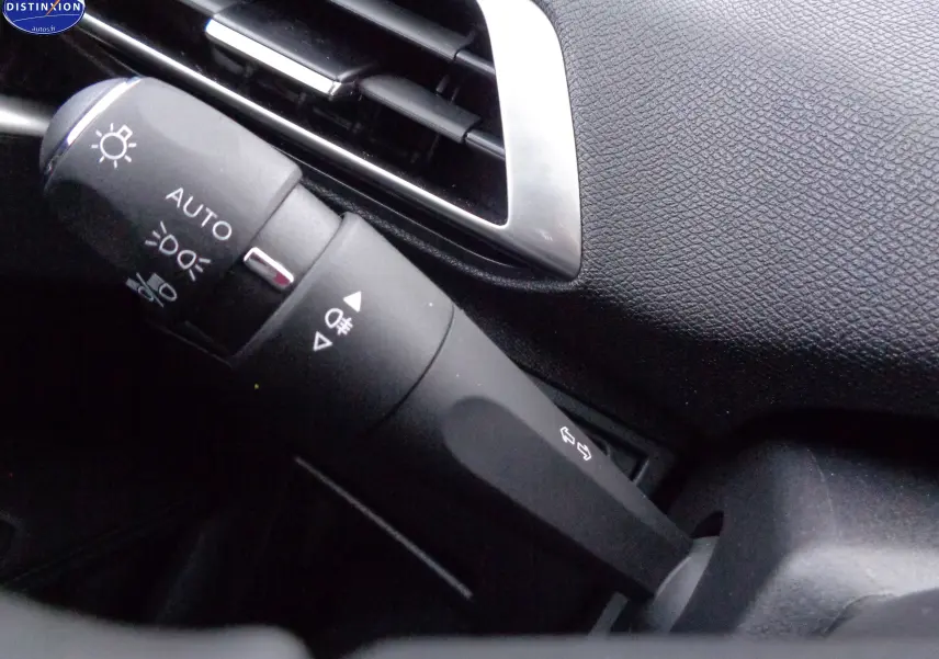 Gros plan sur la commande des feux et clignotants dans l'habitacle noir du Peugeot 3008 2023.