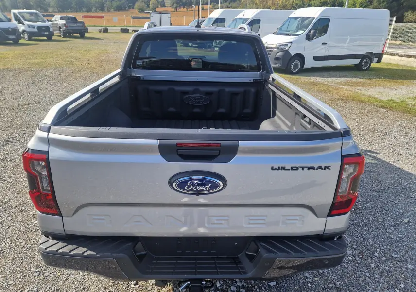 Vue intérieure côté conducteur du Ford Ranger Super Cabine Wildtrak 2025, sièges cuir noirs avec surpiqûres orange et logo brodé.