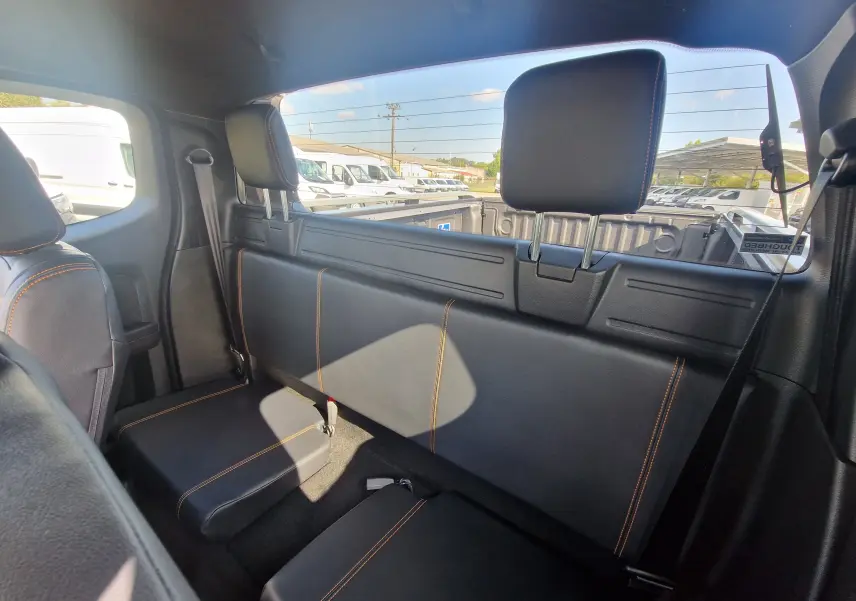 Vue centrée sur le volant cuir noir avec surpiqûres orange du Ford Ranger Wildtrak 2025, tableau de bord digital et écran tactile.