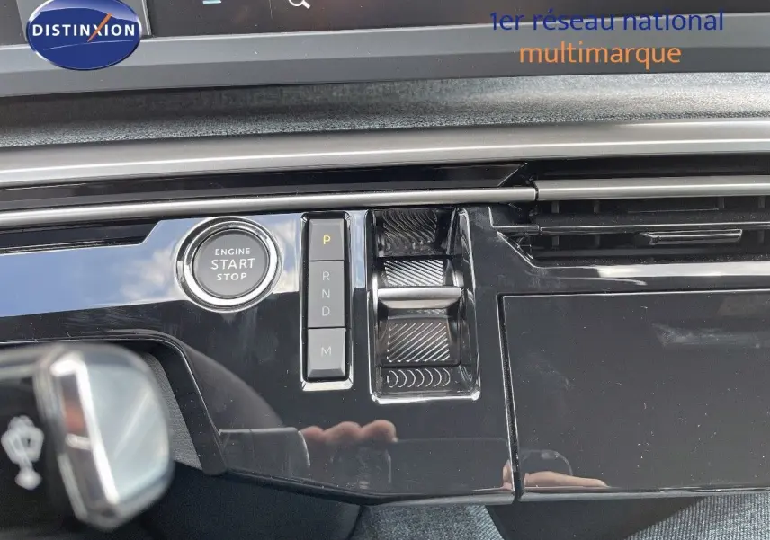 Gros plan sur la console centrale noire brillante du Peugeot 3008 Hybrid 2025 avec bouton start/stop et commandes de boîte automatique.