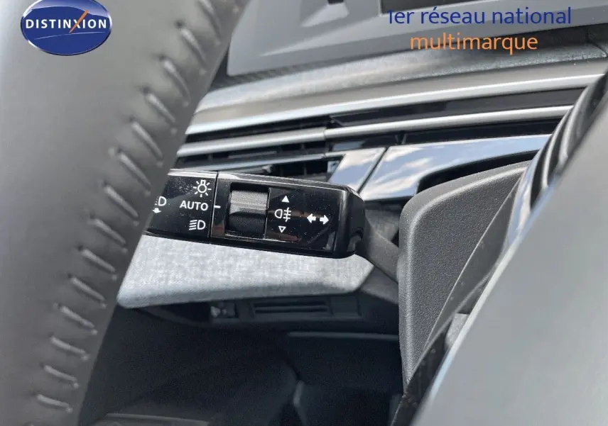 Gros plan sur la commande des feux et clignotants à gauche du volant dans l'habitacle du Peugeot 3008 Hybrid bleu.