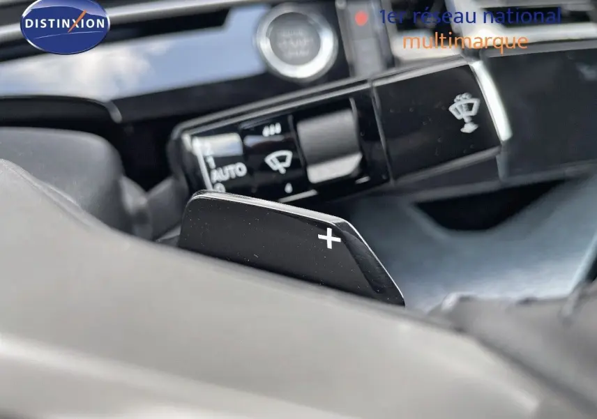 Gros plan sur la palette de changement de vitesse + du Peugeot 3008 Hybrid 2025, intérieur noir avec commandes au volant.