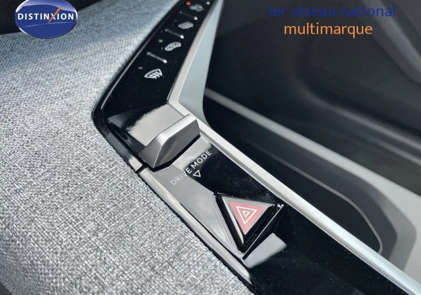 Gros plan sur la console centrale du Peugeot 3008 Hybrid 2025 avec bouton Drive Mode et signal de détresse.