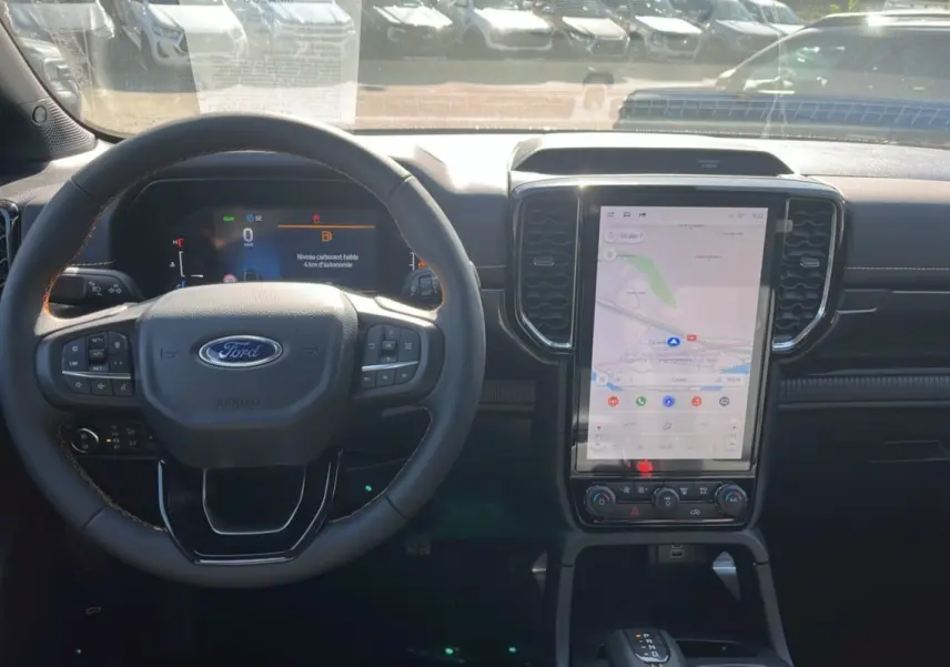Vue intérieure du tableau de bord du Ford Ranger 2.3 PHEV 281 Wildtrak Plus 2025 avec écran tactile vertical et volant multifonction.