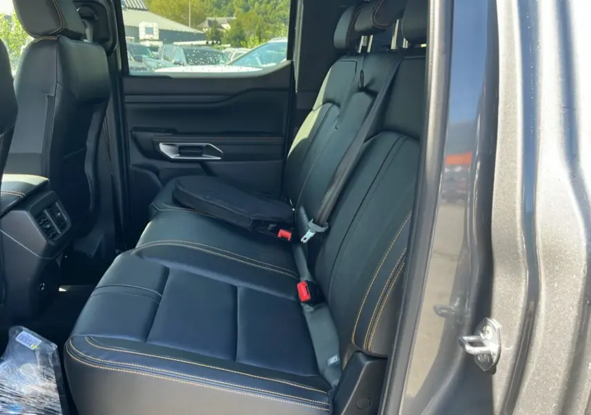 Vue côté droit de l'habitacle arrière du Ford Ranger 2.3 PHEV 281 Wildtrak Plus gris carbone avec sièges en cuir noir et surpiqûres jaunes.