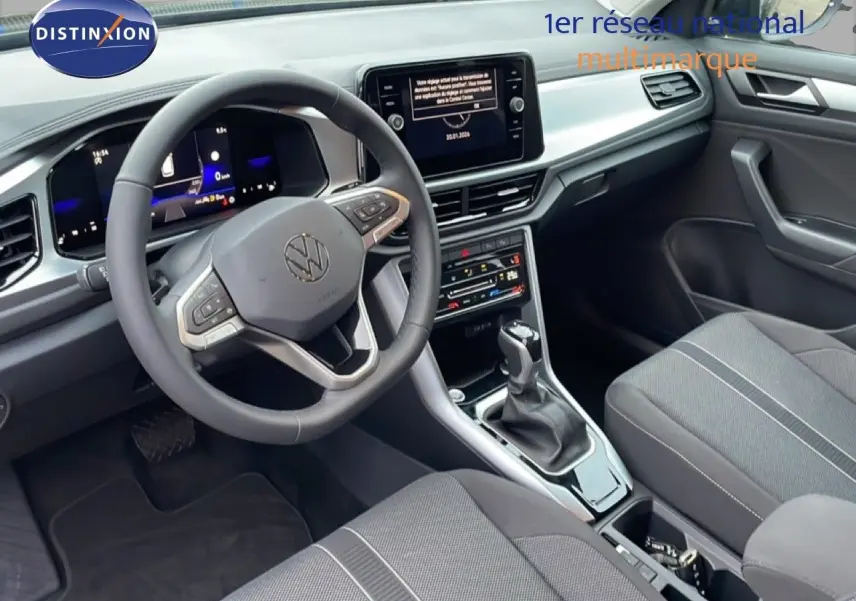 Vue intérieure avant du Volkswagen T-Roc 1.5 TSI noir Grenadilla, avec volant multifonction et écran tactile central.
