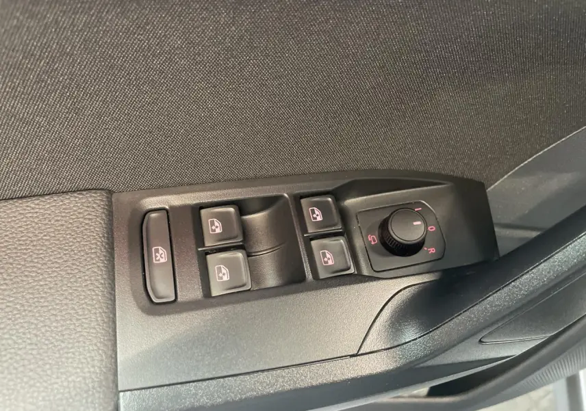Vue rapprochée des commandes des vitres électriques et des rétroviseurs côté conducteur d'une SEAT Arona rouge GRS 2024.