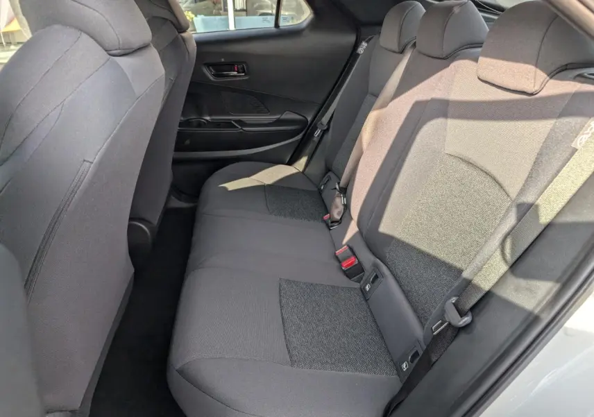 Vue intérieure côté droit des sièges arrière en tissu gris foncé du Toyota C-HR 1.8 Hybrid blanc 2024.