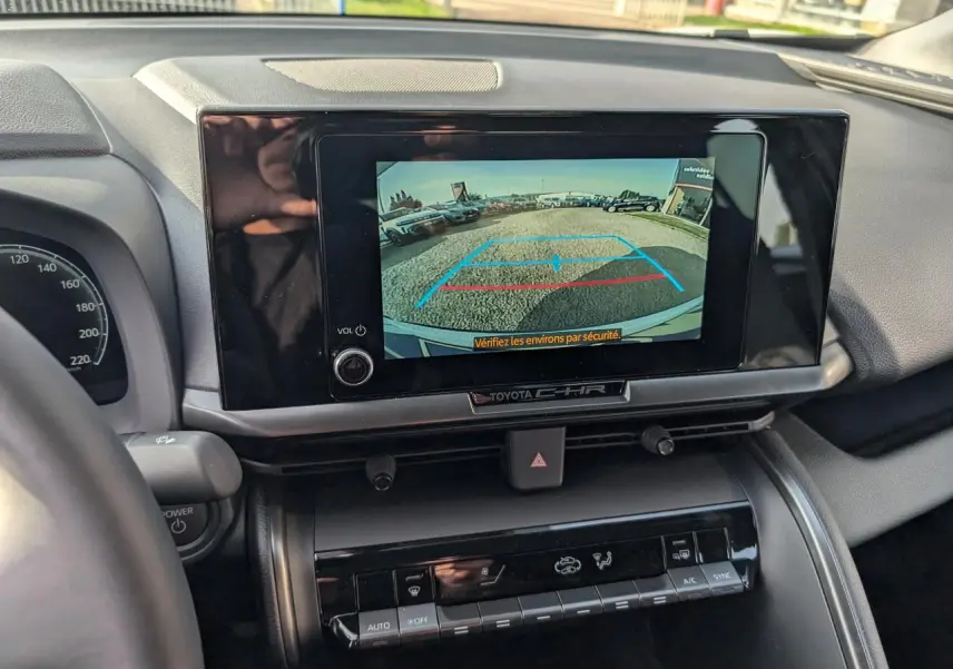 Vue intérieure du tableau de bord du Toyota C-HR blanc 2024, écran tactile affichant la caméra de recul.