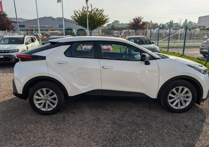 Profil côté gauche du Toyota C-HR 1.8 Hybrid blanc avec jantes alliage 17 pouces et poignées affleurantes.