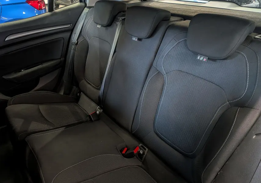 Vue intérieure des sièges arrière en tissu noir de la Renault Mégane IV Berline, avec appuie-têtes et ceintures visibles.