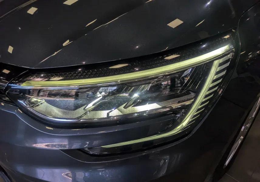 Gros plan sur le phare avant droit LED de la Renault Mégane IV Berline gris Titanium, soulignant ses lignes modernes.