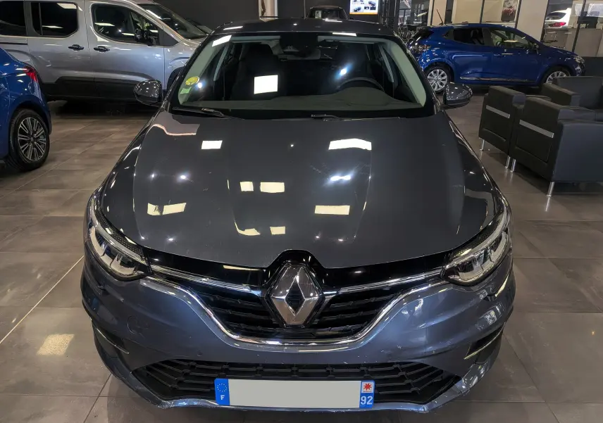 Vue avant d'une Renault Mégane IV Berline gris titanium 2022, avec calandre chromée et logo Renault bien visible.