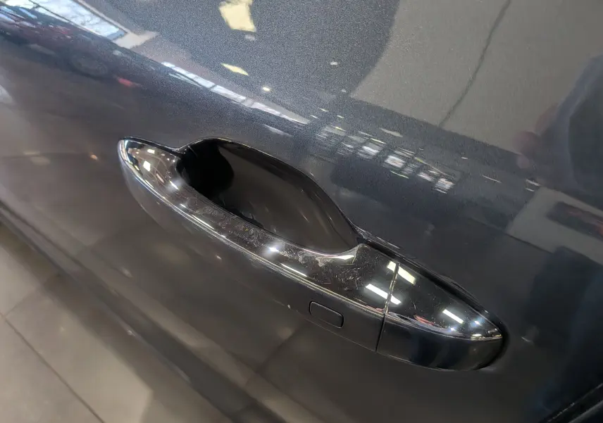 Poignée de porte chromée en gros plan sur la portière gris titanium d'une Renault Mégane IV Berline 2022.