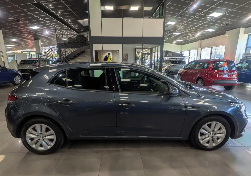 Profil côté gauche de la Renault Mégane IV Berline gris Titanium 2022 en intérieur, mettant en valeur ses lignes épurées.
