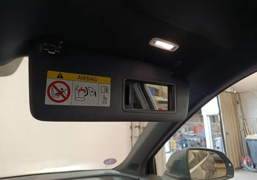 Détail intérieur du pare-soleil côté conducteur avec miroir et étiquette airbag dans un Audi Q5 gris clair 2023 hybride rechargeable.
