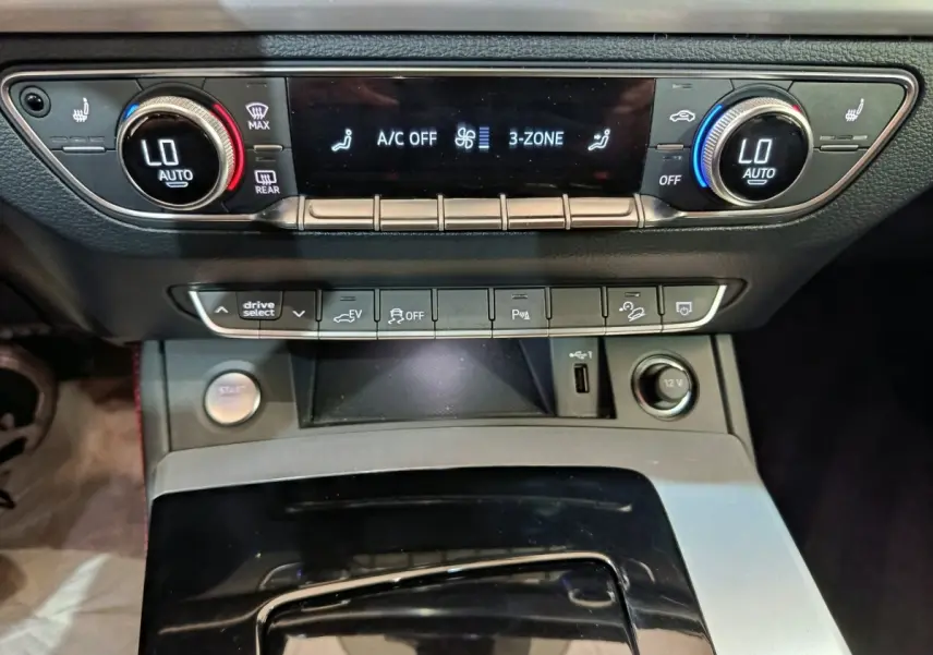 Vue rapprochée du tableau de bord de l'Audi Q5 2023 hybride rechargeable, montrant la climatisation et les commandes centrales.