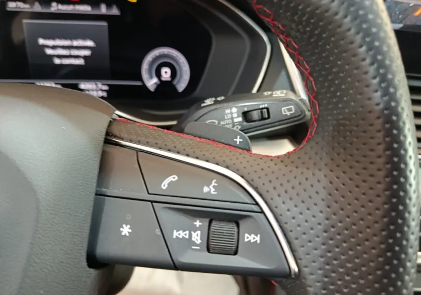 Gros plan sur le volant perforé avec surpiqûres rouges de l'Audi Q5 2023 hybride rechargeable, côté gauche.