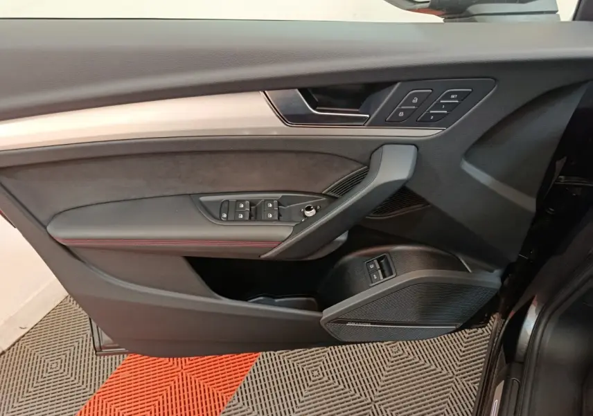 Vue intérieure du panneau de porte côté conducteur de l'Audi Q5 2023 gris clair, avec commandes de vitres et réglages de siège.